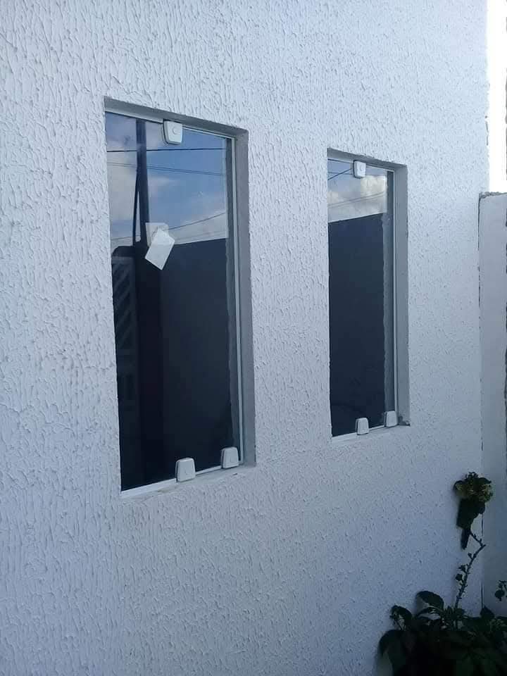 Janelas panorâmicas de vidro em sala de estar com vista para jardim